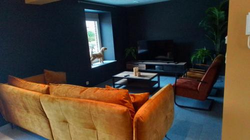 a living room with a brown couch and a tv at La Ferme Villa 2 in Bastogne