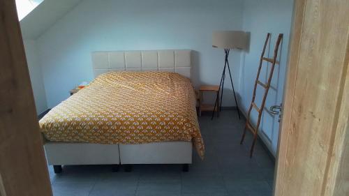 a bedroom with a bed with a yellow blanket at La Ferme Villa 2 in Bastogne