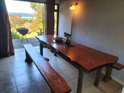 a wooden table and bench in a room with a window at Casa Ariel - River Lodge in Port Edward