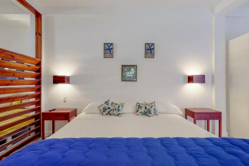 ein Schlafzimmer mit einem großen weißen Bett mit zwei Tischen in der Unterkunft Casa DV Suites Gold Standard Certified in Caye Caulker