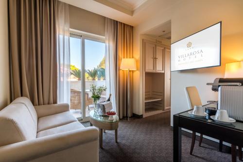 salon z kanapą i oknem w obiekcie Villa Rosa Hotel Desenzano w mieście Desenzano del Garda