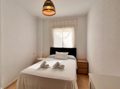 1 dormitorio con 1 cama blanca y 2 toallas en SibsSanlucar Carril SanDiego Centro Familias Garaje, en Sanlúcar de Barrameda