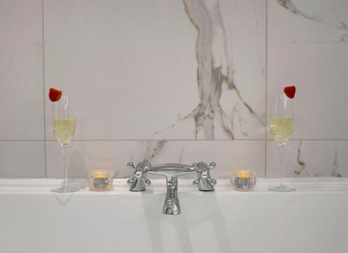 a sink with two glasses of wine and candles at Gleneagles Luxury Apartment in Auchterarder