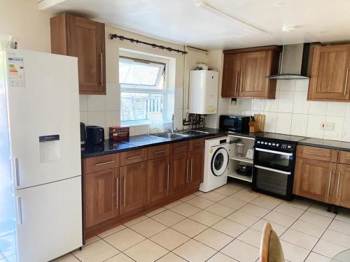 a kitchen with wooden cabinets and a white refrigerator at Single and doubles rooms close to central London in London