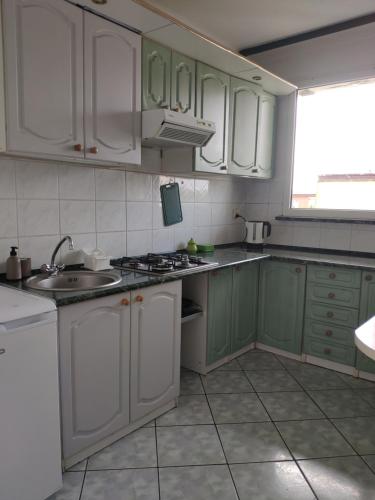 a kitchen with green and white cabinets and a sink at Mieszkanie Mrzeżyno/Rogowo in Rogowo