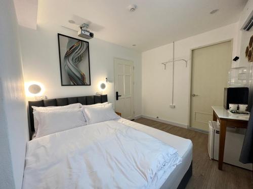 a bedroom with a white bed and a desk at The White Den Sukhumvit 44 in Bangkok