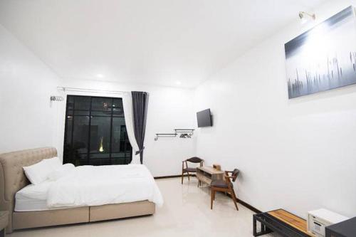a white bedroom with a bed and a desk and a window at Na Klongluang Boutique Resort in Ban Khlong Nung