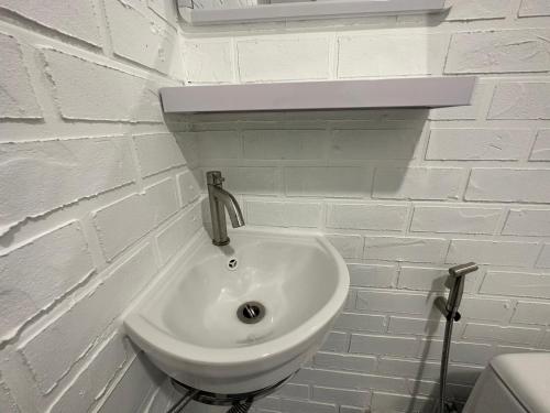 a white sink in a white brick wall at The White Den Sukhumvit 44 in Bangkok