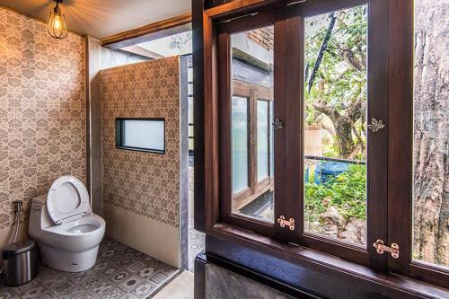 a bathroom with a toilet and a window at Na Klongluang Boutique Resort in Ban Khlong Nung