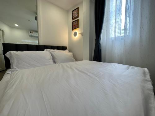 a white bed with white sheets and a window at The White Den Sukhumvit 44 in Bangkok