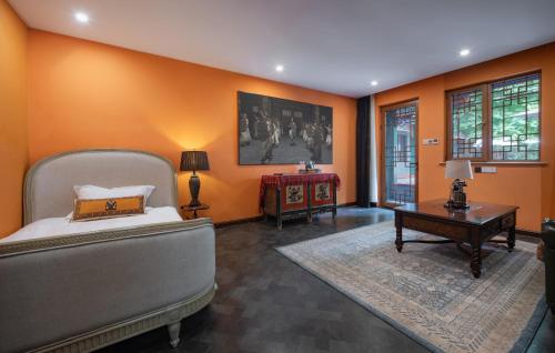 a bedroom with orange walls and a bed and a table at Hotel Cote Cour Deductive Beijing - Quadrangle close to Tiananmen Square & Forbidden City & Nanluoguxiang, Walk to Wangfujing, English speaking, Free WiFi, Free Laundry, Free Wonton & Noodles with Tour ticket service, Free selfies with ancient costume in Beijing