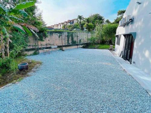 a gravel driveway in a yard next to a building at Cheerful 27 Home with BBQ grill in Cheras