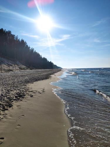 a beach with the sun shining on the water at Mieszkanie Mrzeżyno/Rogowo in Rogowo