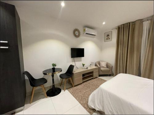 um quarto de hotel com uma cama, uma secretária e uma cadeira em Studio unit @ Airport The Lennox em Accra