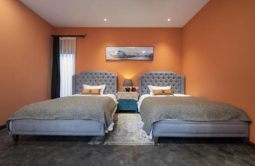 two beds in a room with orange walls at Hotel Cote Cour Deductive Beijing - Quadrangle close to Tiananmen Square & Forbidden City & Nanluoguxiang, Walk to Wangfujing, English speaking, Free WiFi, Free Laundry, Free Wonton & Noodles with Tour ticket service, Free selfies with ancient costume in Beijing