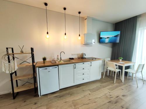 a kitchen with white cabinets and a table and a tv at K-Town - Apartments ViaBaltic Kaunas in Kaunas