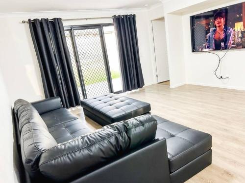 a living room with a black leather couch and a tv at Stay at Mandi’s in Kingston