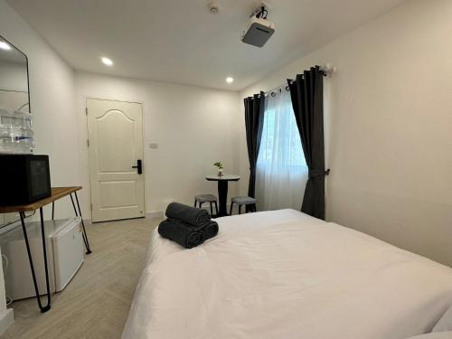 a bedroom with a bed and a television and a table at The White Den Sukhumvit 44 in Bangkok