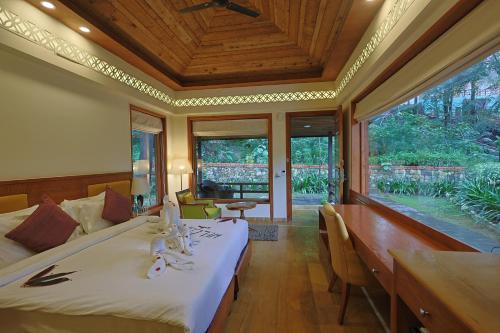 Punarnava Resort & Spa في دهرادون: غرفة نوم بسرير وطاولة وكراسي