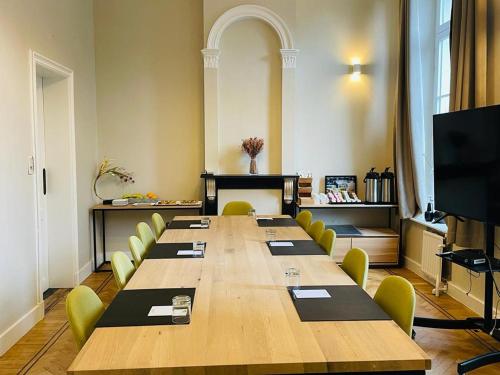 Parkhotel Gent Centrum في خنت: قاعة اجتماعات كبيرة مع طاولة طويلة وكراسي صفراء