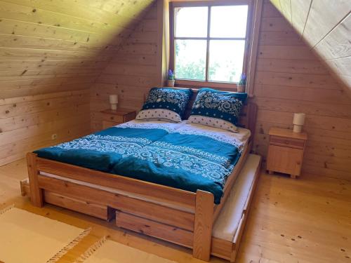 a bed in a log cabin with a window at Pod Gwiazdami in Dąbrówka