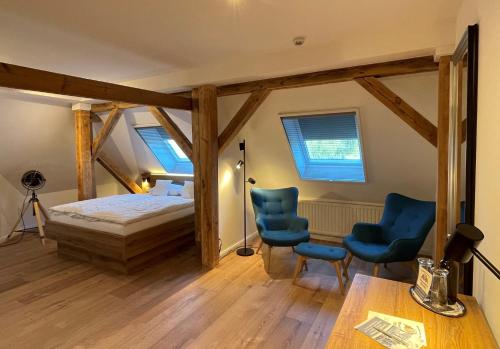a bedroom with a bed and two blue chairs at Hotel Wasserschloss Mellenthin in Mellenthin
