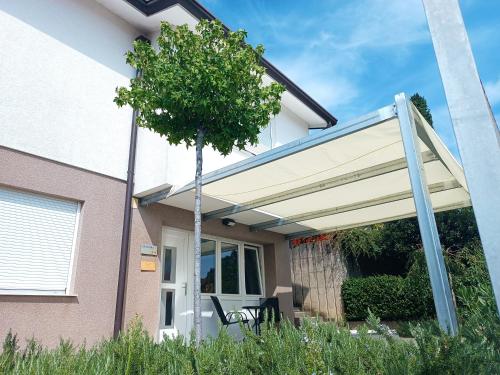 awning over a porch of a house with a tree at Apartma 31 in Nova Gorica