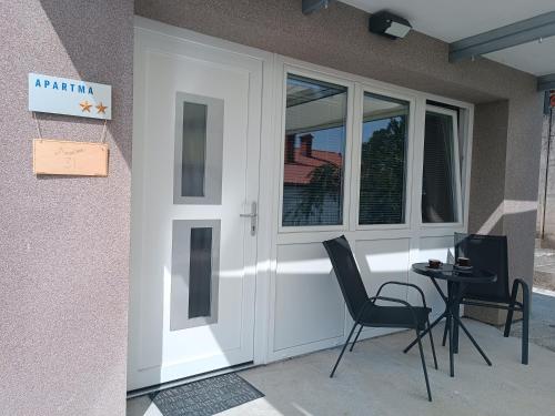 eine weiße Eingangstür mit 2 Stühlen und einem Tisch in der Unterkunft Apartma 31 in Nova Gorica