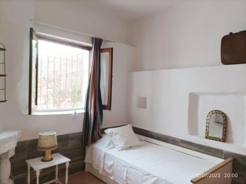 1 dormitorio con cama, ventana y lavamanos en Casa rural con piscina, en Torre de Benagalbón