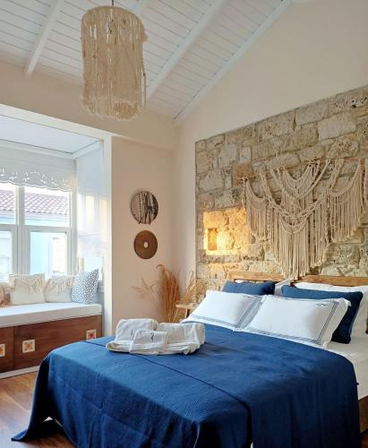 ein Schlafzimmer mit einem blauen Bett und einer Steinwand in der Unterkunft Adacan Hotel Alaçatı in Alacati