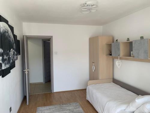 a white bedroom with a bed and a closet at Victoriei Boulevard Private Apartment in Braşov
