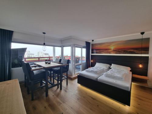 a bedroom with a bed and a table and a dining room at LITTLE SKYSUITE Terrassenhaus W 94 in Cuxhaven