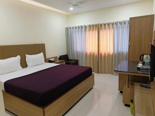 a bedroom with a bed and a desk and a television at HOTEL PRITAM PARK in Jālgaon