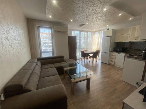 a living room with a couch and a table and a kitchen at Cozy-1BD Flat in Plovdiv