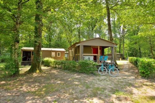 eine Hütte im Wald mit einem Fahrrad vor dem Haus in der Unterkunft Camping Etang de la Vallée in Combreux