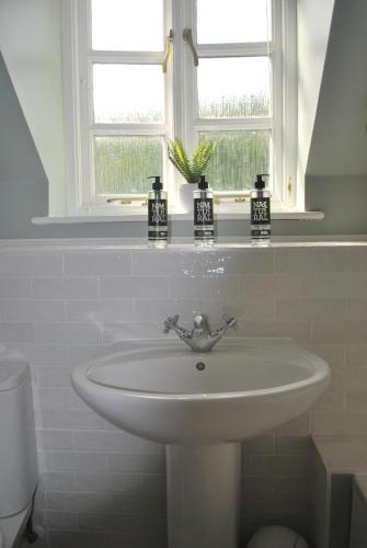 New - Beautiful Countryside Home في ستريتلي: بالوعة بيضاء في الحمام مع نافذة
