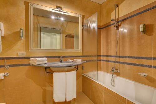 La salle de bains est pourvue d'un lavabo, d'un miroir et d'une baignoire. dans l'établissement Hotel Continental Brescia, à Roncadelle