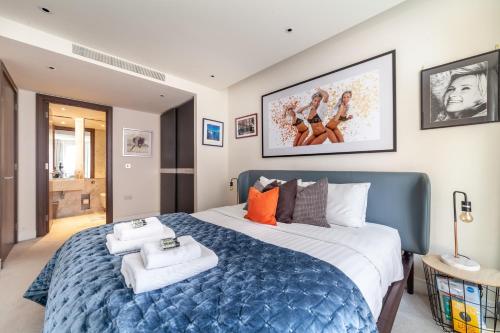 a bedroom with a large blue bed with towels on it at Stylish 2-BR ground floor apt in Chelsea in London