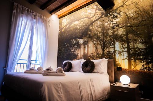 una camera da letto con un letto, asciugamani e una finestra di Old Town - Boutique Rooms a Modena