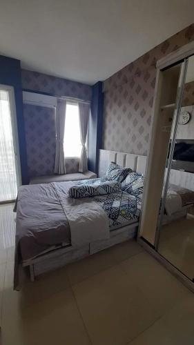 um quarto com uma cama e um espelho em Vin's Room at Vivo Apartemen em Seturan
