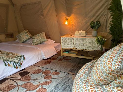 深セン市にあるNatureLand Campsiteのベッド2台、テーブル(ランプ付)が備わるテントルームです。
