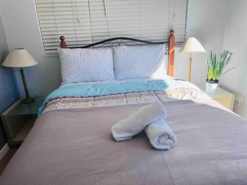 uma toalha branca deitada numa cama com dois candeeiros em Double bedroom in Sharehouse in Canberra and Queanbeyan em Queanbeyan