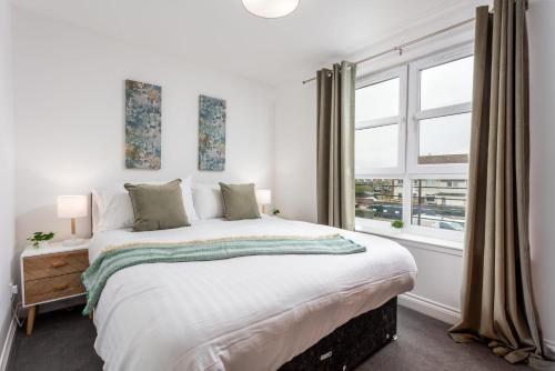 a white bedroom with a large bed and a window at Elms Way No33 – Donnini Apartments in Ayr