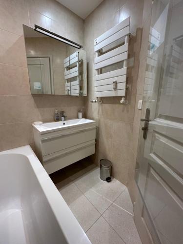 La salle de bains est pourvue d'un lavabo, d'une baignoire et d'un miroir. dans l'établissement Appartement Rottaro luxueux 2 ch 2 sdb face à la mer, à Cannes