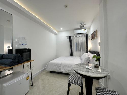 a bedroom with a bed and a table with chairs at The White Den Sukhumvit 44 in Bangkok