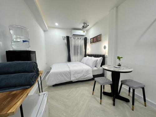 a bedroom with a bed and a table and chairs at The White Den Sukhumvit 44 in Bangkok
