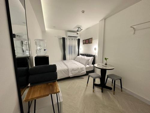 a bedroom with a bed and a table and a mirror at The White Den Sukhumvit 44 in Bangkok