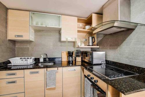 a kitchen with wooden cabinets and a stove top oven at CR MARIPOSA RENTALS Comfortable penthouse, AC, pool, gym, tennis in Santa Ana