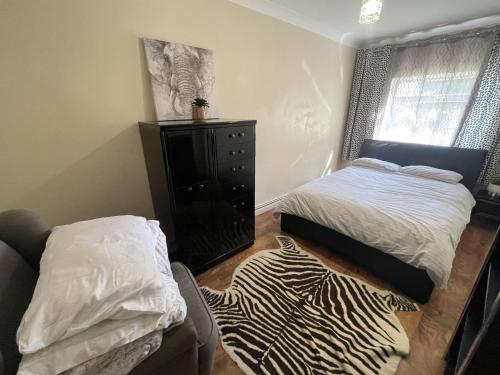 a bedroom with a bed and a dresser and a zebraebra rug at Lovely 1 bedroom apartment with garden in London