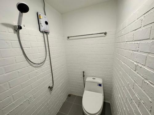 a white bathroom with a toilet and a shower at The White Den Sukhumvit 44 in Bangkok